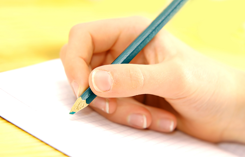 Une main tient un crayon de couleur, avec une bonne prise tridigitale
